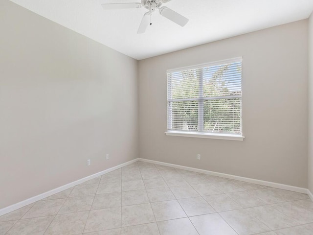 spare room featuring a ceiling fan, light tile patterned flooring, and baseboards