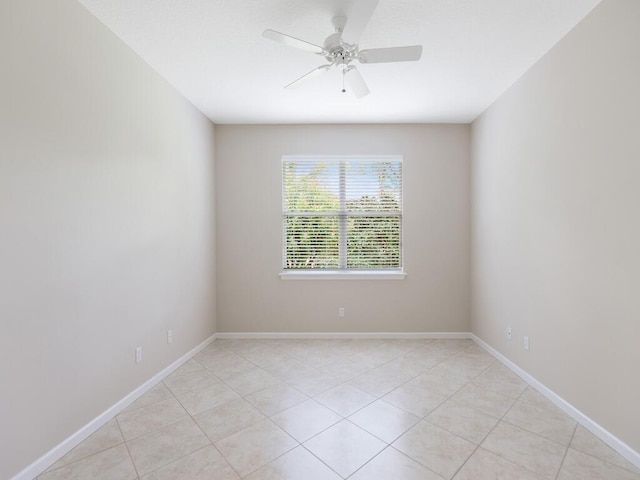 empty room featuring light tile patterned flooring, a ceiling fan, and baseboards