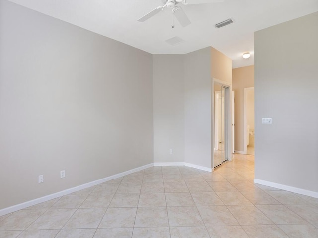 empty room featuring ceiling fan, light tile patterned floors, visible vents, and baseboards