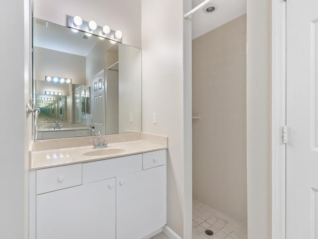 bathroom with a tile shower and vanity