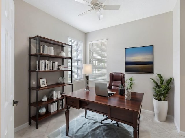 office space with a ceiling fan, baseboards, and light tile patterned floors