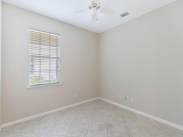 empty room with light tile patterned flooring, ceiling fan, visible vents, and baseboards