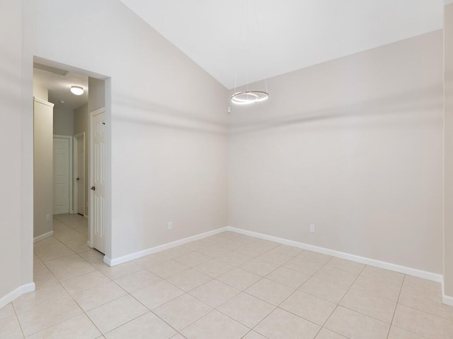 unfurnished room with lofted ceiling, light tile patterned floors, and baseboards