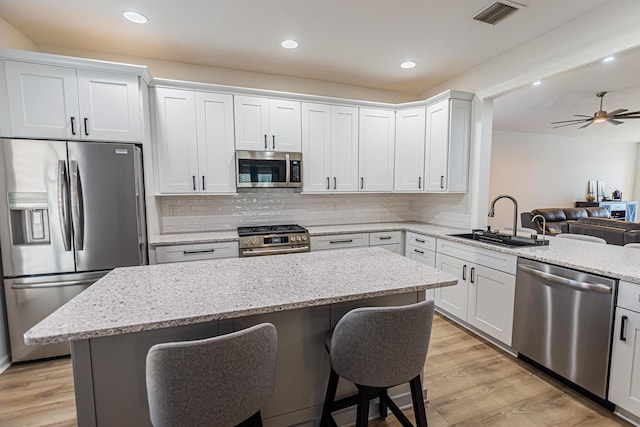 kitchen with stainless steel appliances, visible vents, light wood-style floors, a sink, and a kitchen breakfast bar