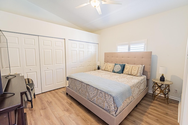 bedroom featuring two closets, lofted ceiling, light wood-style flooring, ceiling fan, and baseboards