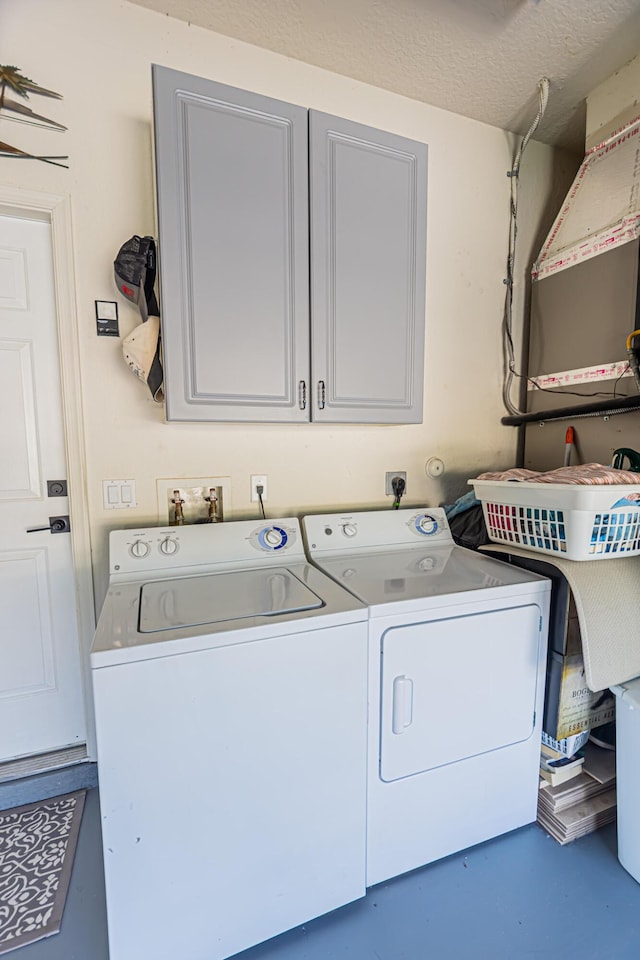 washroom with cabinet space, washing machine and dryer, and a textured ceiling