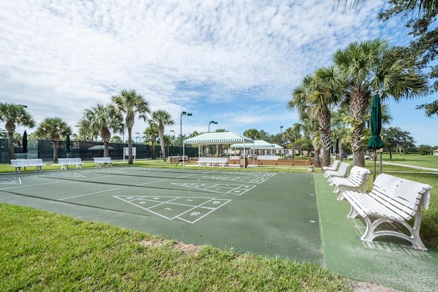 view of property's community featuring fence and shuffleboard