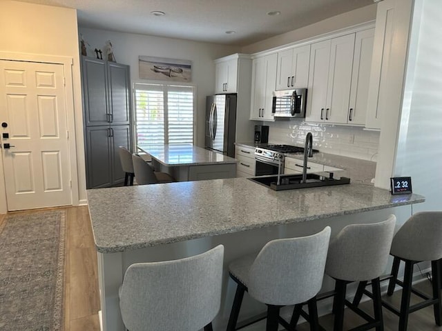 kitchen featuring backsplash, wood finished floors, a center island, stainless steel appliances, and a sink