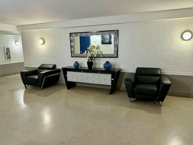 sitting room featuring speckled floor and a textured wall