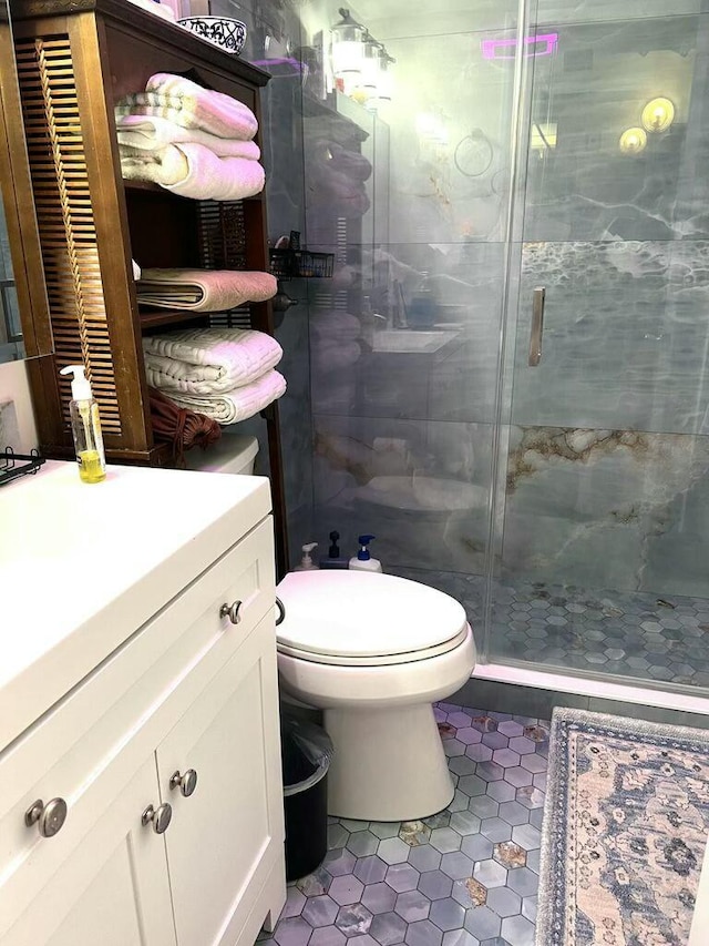 bathroom featuring toilet, a stall shower, vanity, and tile patterned floors