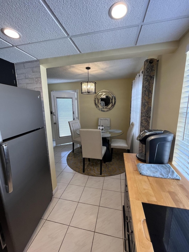 dining area featuring a paneled ceiling, light tile patterned flooring, and baseboards