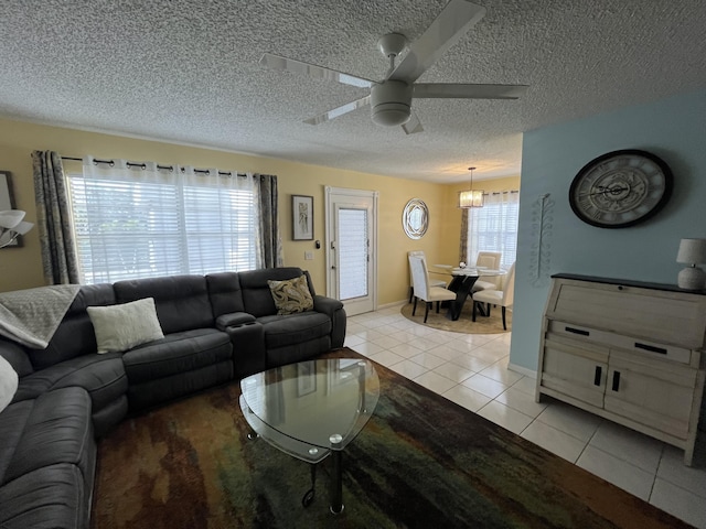 living area featuring ceiling fan, a textured ceiling, baseboards, and light tile patterned floors