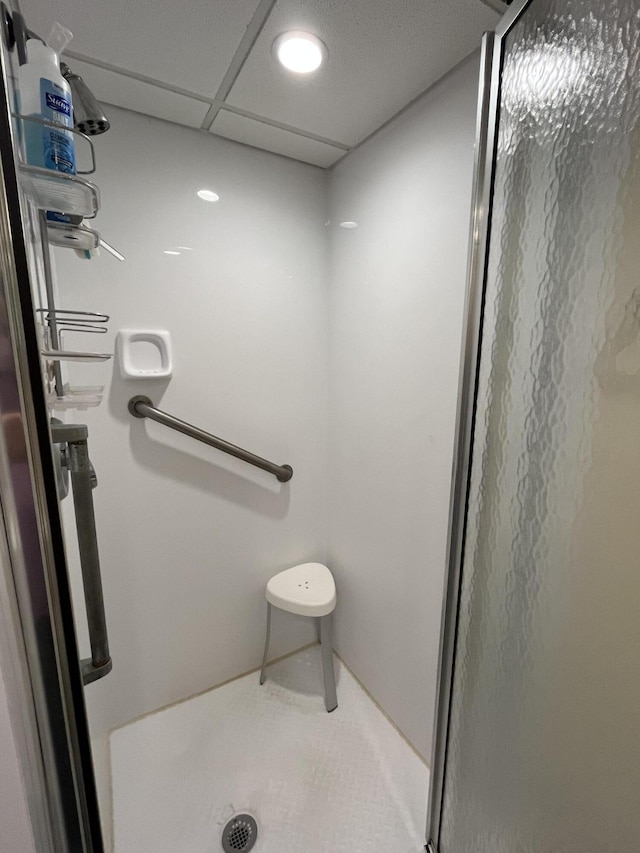 bathroom with a stall shower, tile patterned flooring, and a drop ceiling