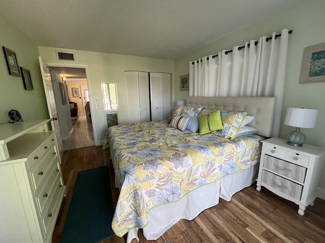 bedroom with a closet, dark wood-style flooring, visible vents, and a textured ceiling