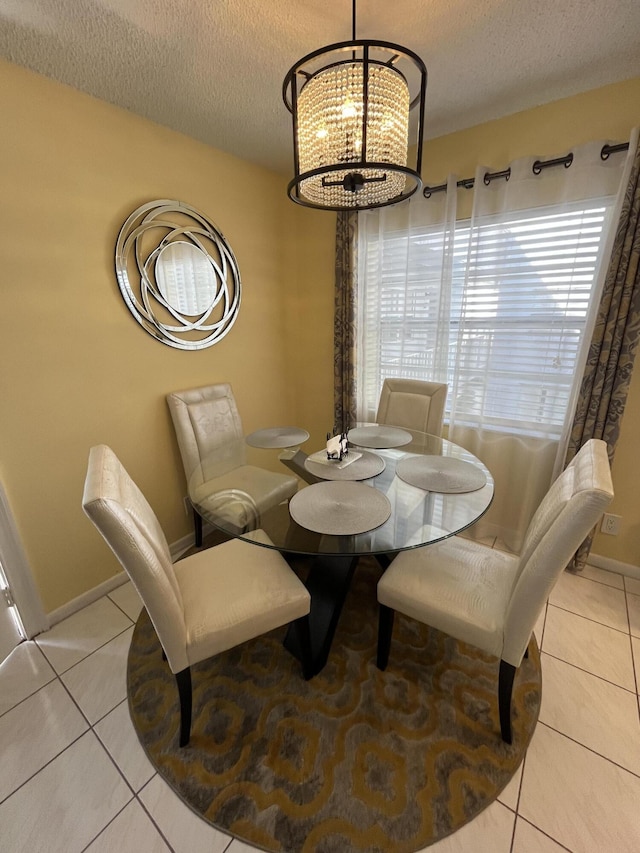 tiled dining space with a textured ceiling, a chandelier, and baseboards