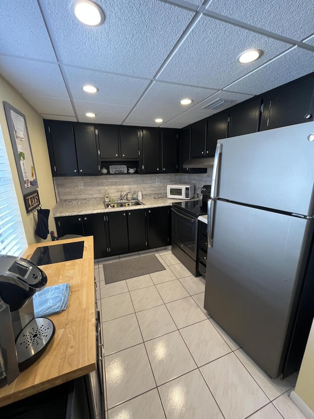 kitchen with visible vents, white microwave, dark cabinets, freestanding refrigerator, and range with electric stovetop