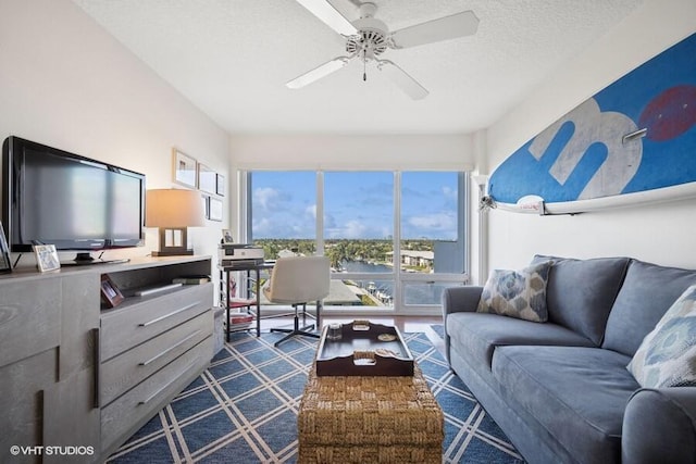 living area featuring ceiling fan and a textured ceiling