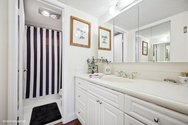 full bath with toilet, curtained shower, a textured ceiling, and vanity