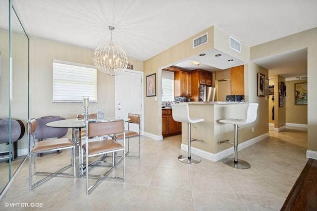 dining room with a notable chandelier, light tile patterned flooring, visible vents, and baseboards