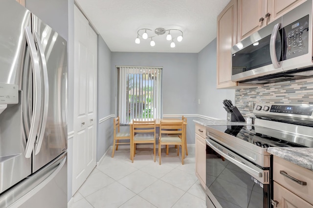 kitchen with appliances with stainless steel finishes, light tile patterned flooring, and backsplash