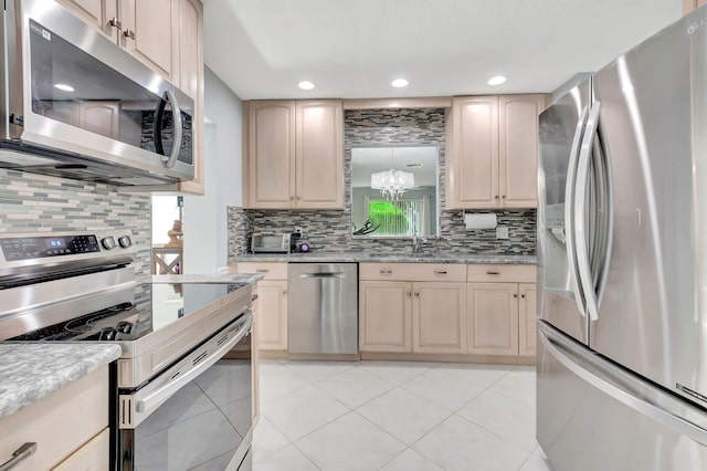 kitchen with appliances with stainless steel finishes, light tile patterned flooring, and tasteful backsplash