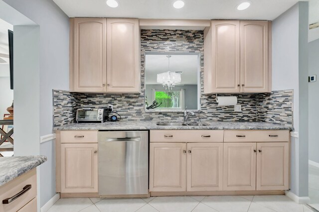 kitchen with dishwasher, a sink, and light brown cabinets