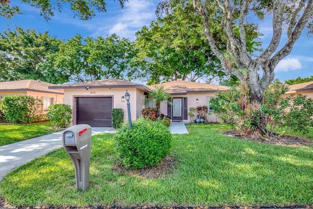 ranch-style home with a garage, concrete driveway, a front yard, and stucco siding