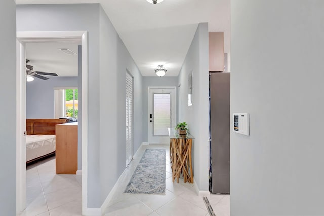 hall featuring light tile patterned flooring and baseboards