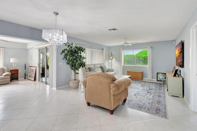 living room with light tile patterned floors, ceiling fan with notable chandelier, visible vents, and baseboards