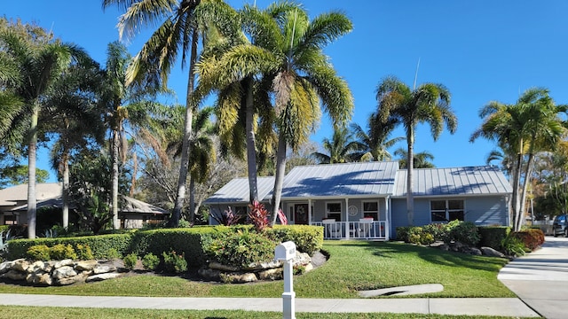 ranch-style home with a porch, a front yard, a standing seam roof, and metal roof