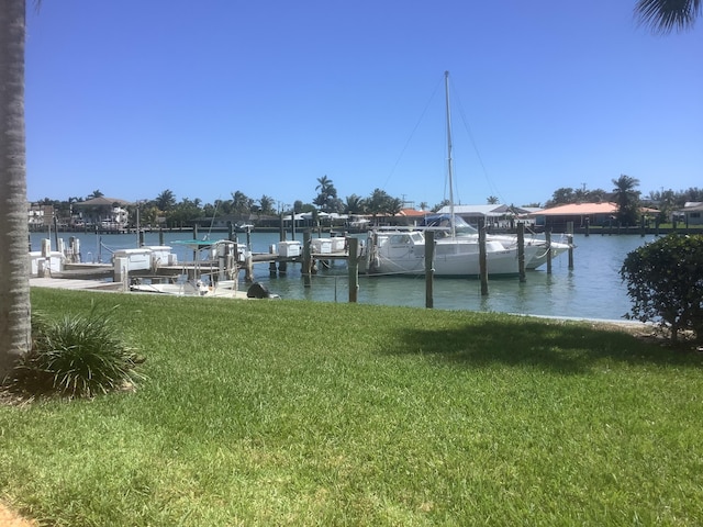 view of dock with a lawn and a water view