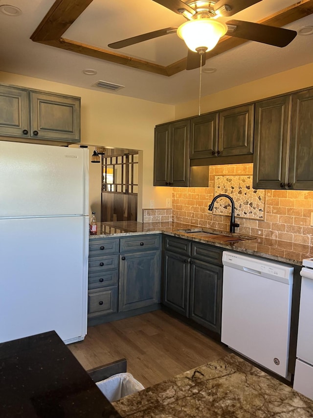 kitchen with visible vents, decorative backsplash, wood finished floors, white appliances, and a sink