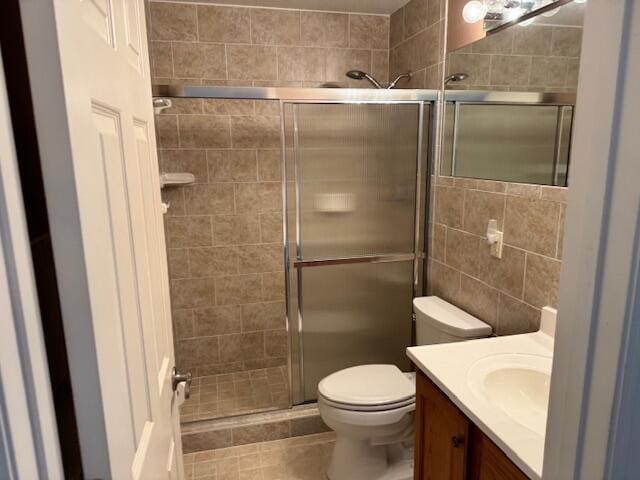 bathroom featuring toilet, a stall shower, and vanity