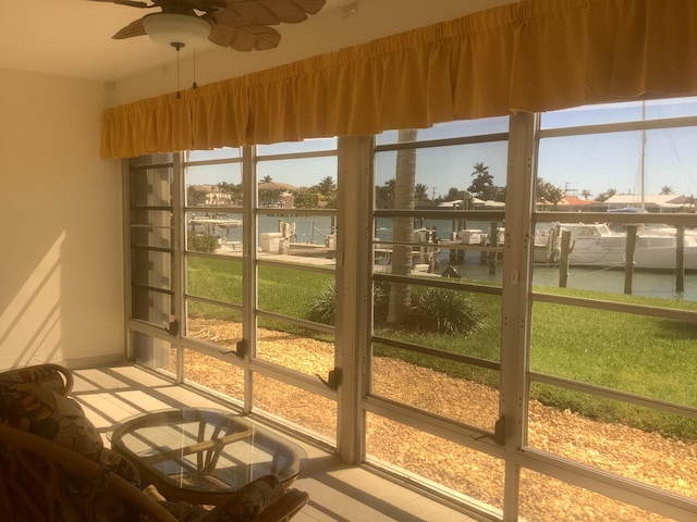 sunroom with a water view and ceiling fan