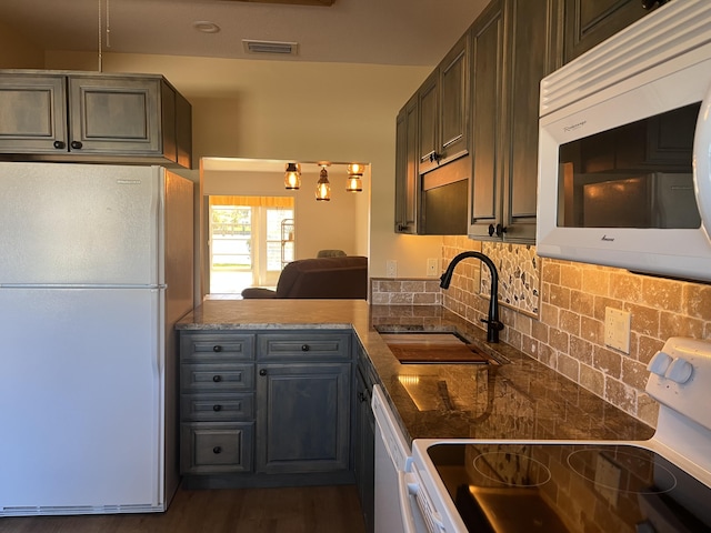 kitchen with visible vents, dark wood-type flooring, decorative backsplash, white appliances, and a sink