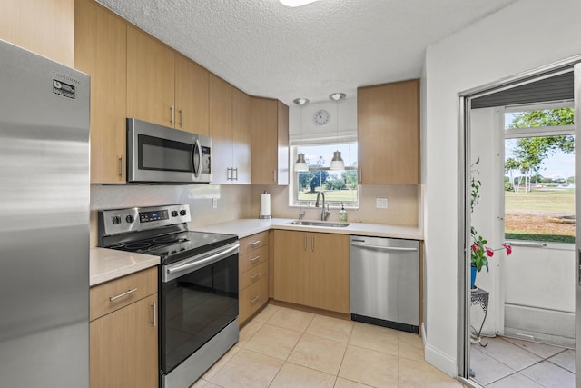 kitchen with a sink, appliances with stainless steel finishes, a healthy amount of sunlight, and light countertops