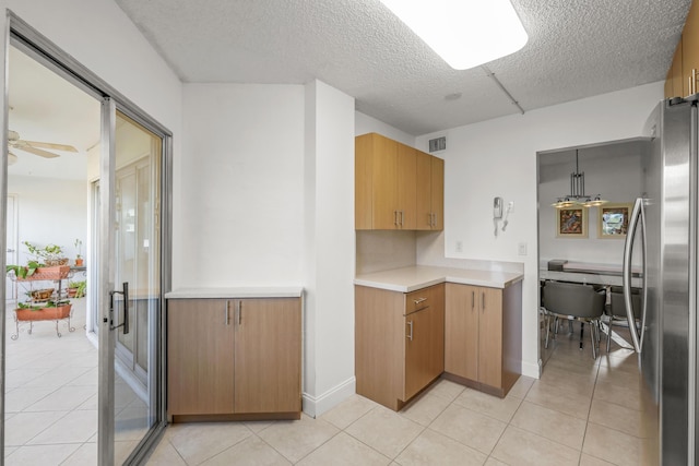 kitchen featuring light countertops, light tile patterned flooring, visible vents, and freestanding refrigerator