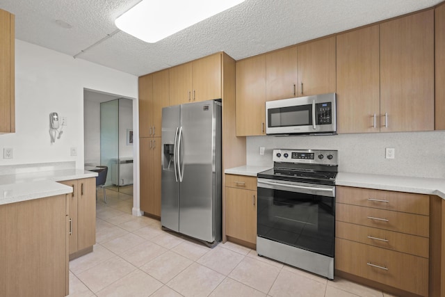 kitchen featuring light countertops, light tile patterned floors, appliances with stainless steel finishes, and a textured ceiling