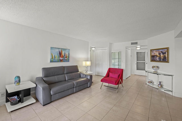 living room featuring light tile patterned floors, visible vents, and a textured ceiling