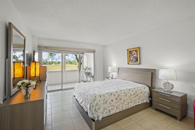 bedroom featuring access to exterior, light tile patterned floors, and a textured ceiling