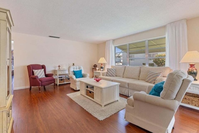 living room with dark wood-style floors, a textured ceiling, and visible vents