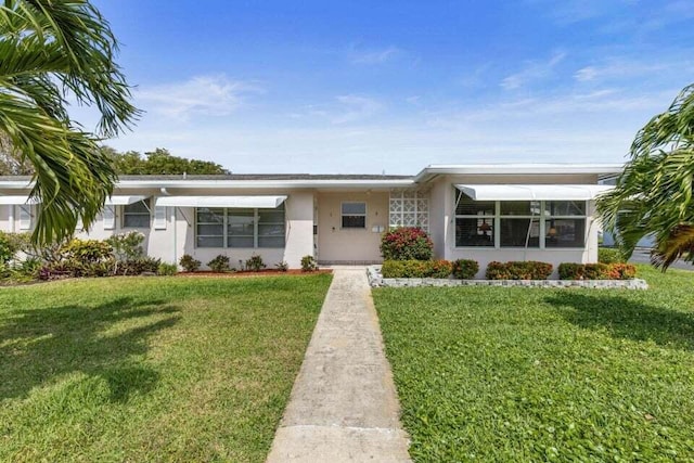 ranch-style house featuring a front lawn and stucco siding