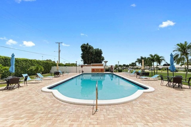 pool with a patio area and fence