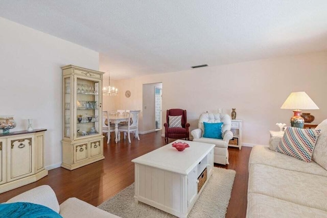 living room with baseboards, visible vents, a chandelier, and wood finished floors