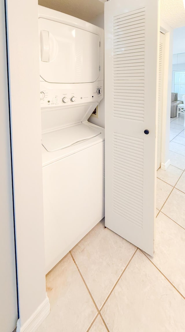 washroom featuring stacked washer and clothes dryer, light tile patterned floors, and laundry area