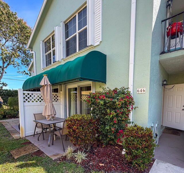 property entrance featuring fence, a patio, and stucco siding