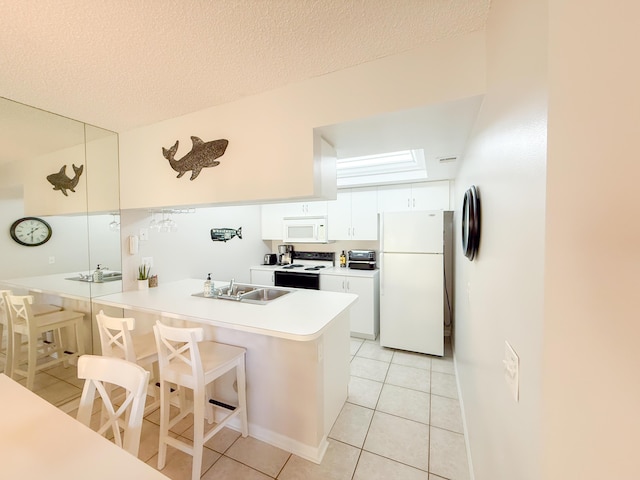 kitchen featuring a peninsula, white appliances, a sink, white cabinetry, and a kitchen bar