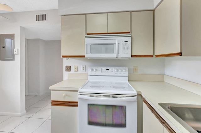 kitchen featuring cream cabinetry, light tile patterned floors, light countertops, white appliances, and electric panel