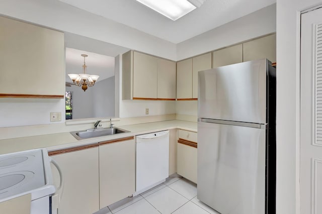 kitchen featuring white appliances, cream cabinets, a sink, a chandelier, and light countertops