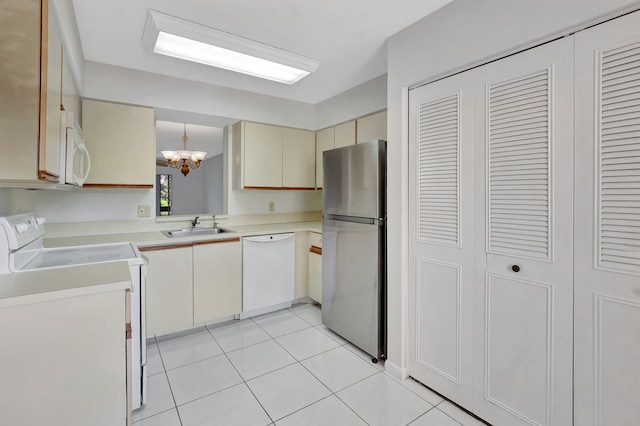 kitchen with white appliances, light tile patterned floors, cream cabinets, light countertops, and a sink